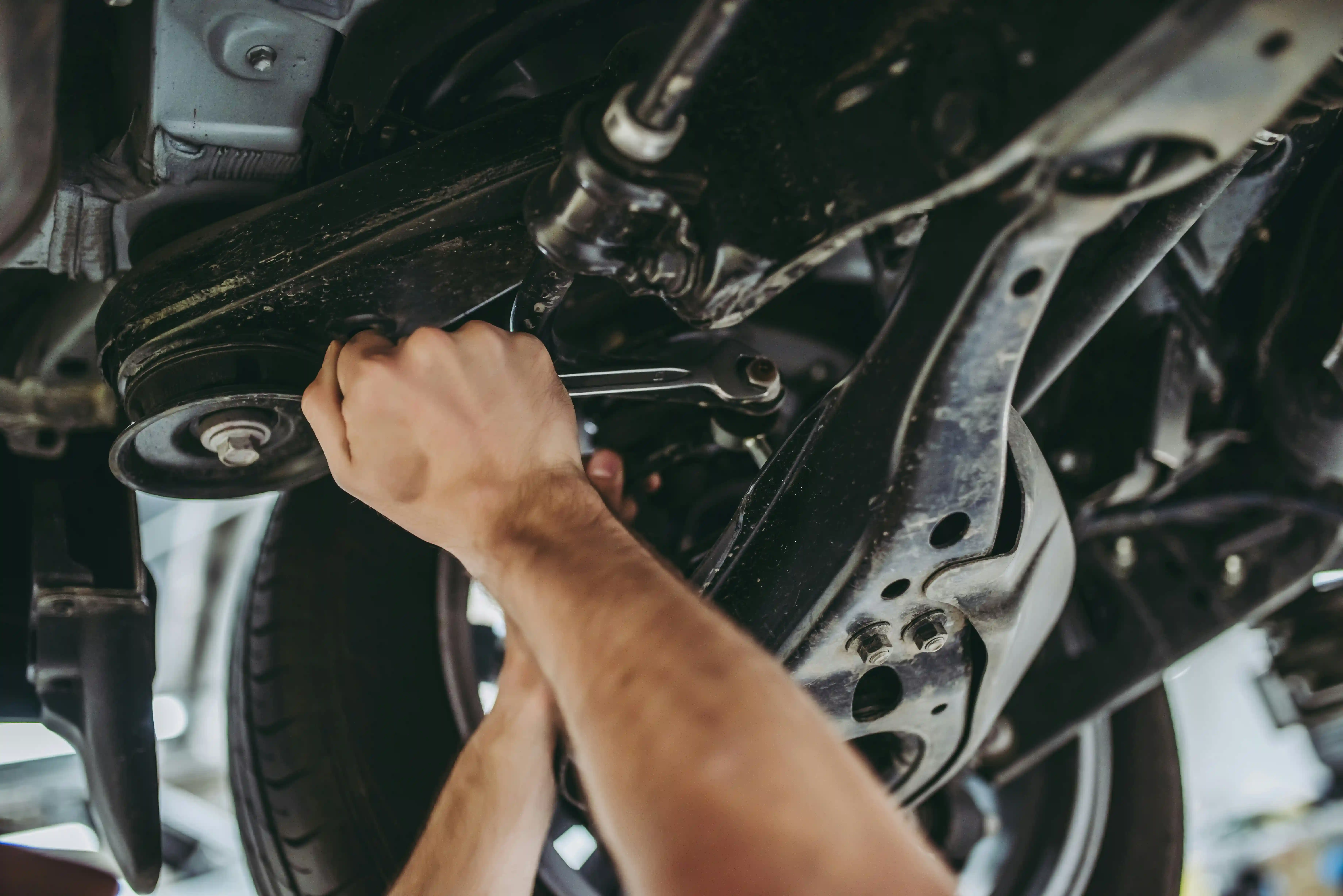 Monteur repareert onderdelen onder een opgekrikte auto